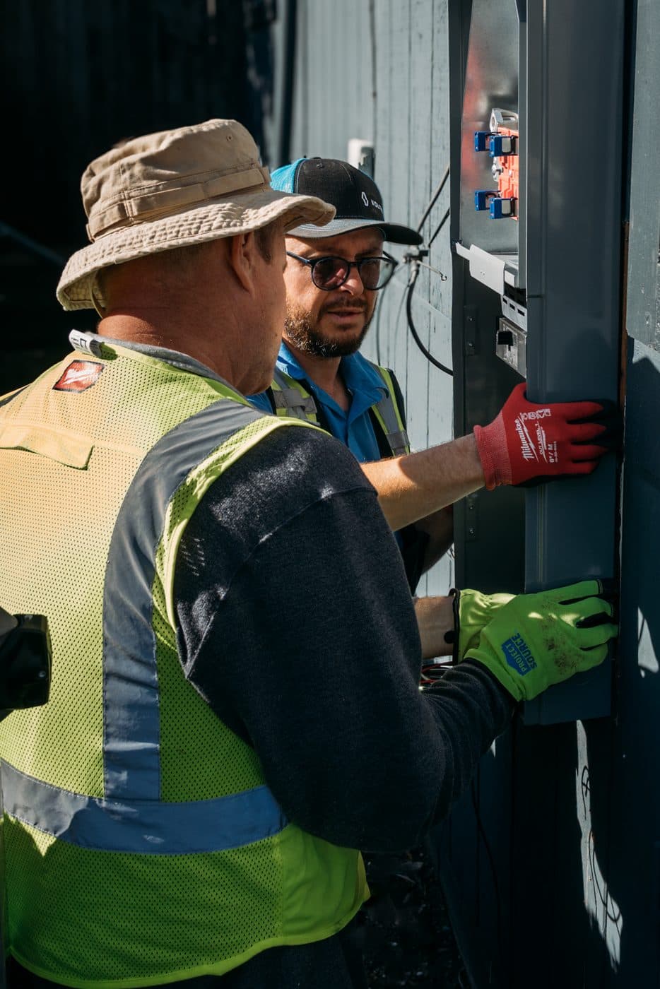 Two electricians working inside a commercial panel